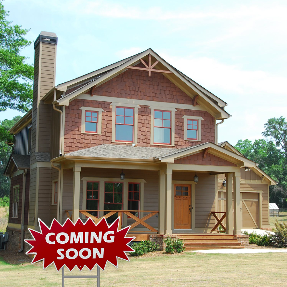 Brown house with a red burst sign in front that says "coming soon"
